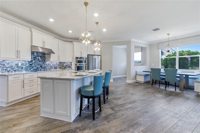 kitchen featuring white cabinetry, decorative light fixtures, and a kitchen island with sink