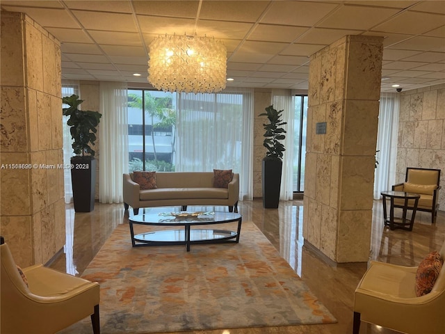 living room featuring a paneled ceiling, a notable chandelier, and floor to ceiling windows