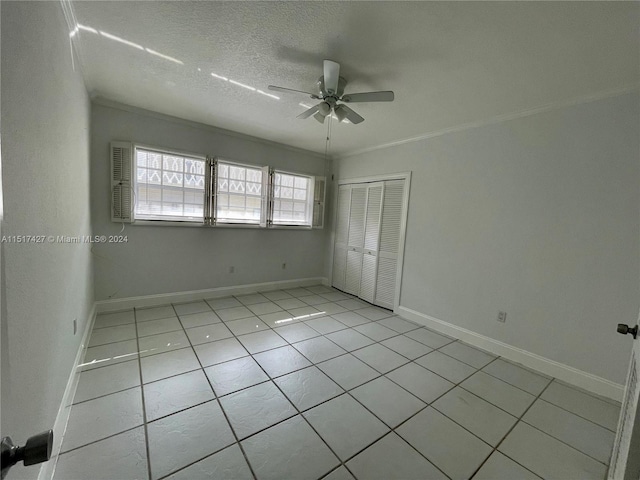 unfurnished room with a textured ceiling, ornamental molding, light tile flooring, and ceiling fan