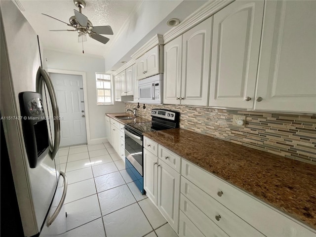 kitchen featuring white cabinetry, backsplash, ceiling fan, stainless steel appliances, and dark stone counters