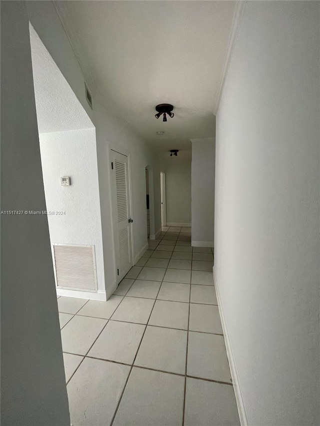 hallway featuring ornamental molding and light tile floors