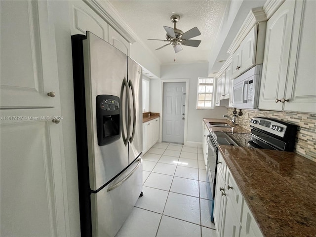 kitchen featuring white cabinetry, ceiling fan, light tile flooring, stainless steel appliances, and tasteful backsplash