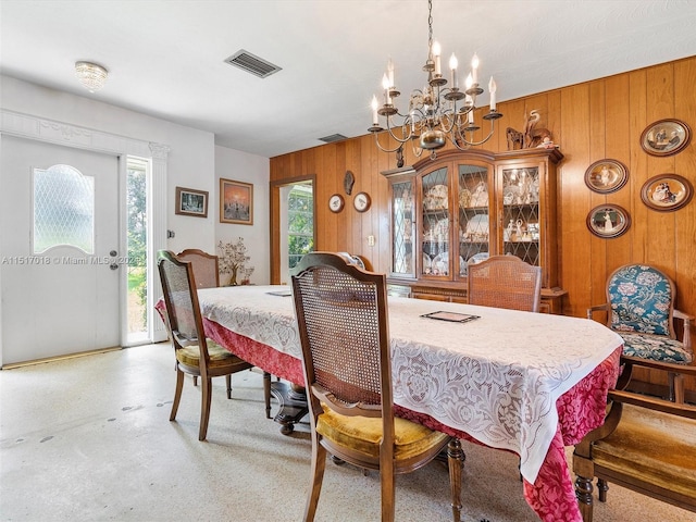 dining room with wooden walls and a chandelier