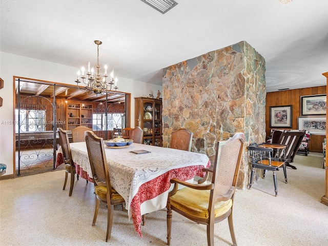 dining area featuring wood walls and a chandelier