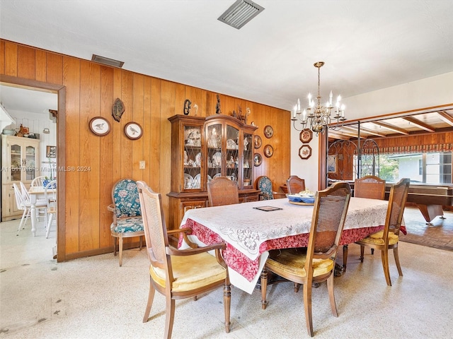 dining room featuring a notable chandelier and wooden walls