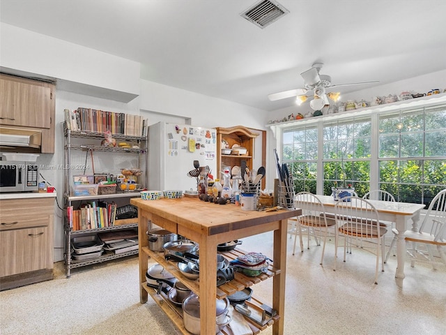 kitchen featuring light brown cabinetry, white fridge, and ceiling fan