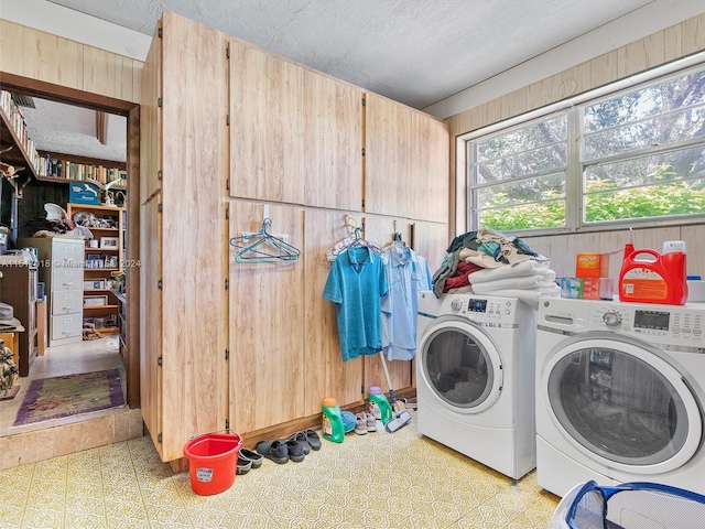 washroom featuring washer and clothes dryer, wood walls, and light tile patterned floors