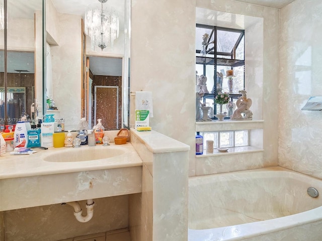 bathroom with a washtub, a notable chandelier, and vanity