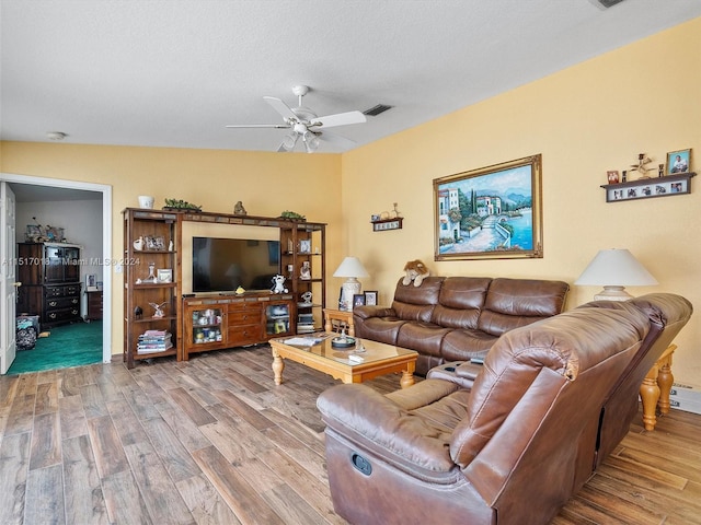 living room with a textured ceiling, ceiling fan with notable chandelier, wood-type flooring, and vaulted ceiling