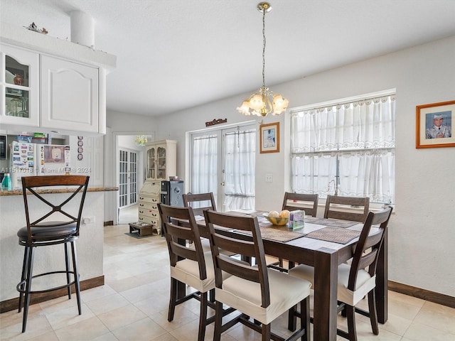 tiled dining space with a healthy amount of sunlight, french doors, and a chandelier