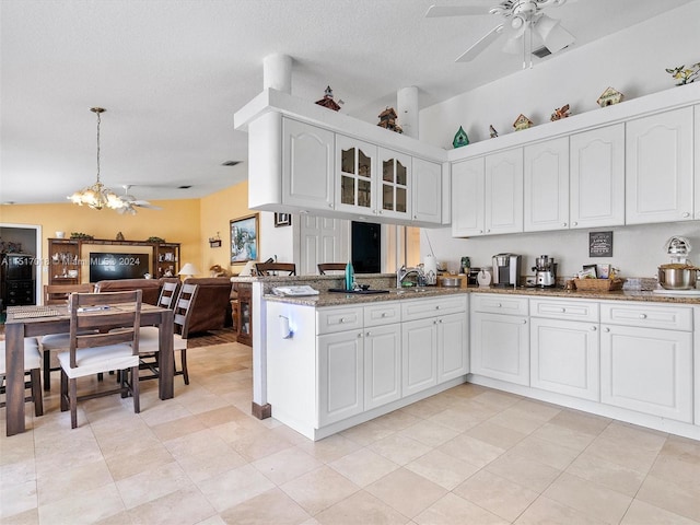 kitchen with stone counters, light tile patterned flooring, ceiling fan with notable chandelier, and white cabinets