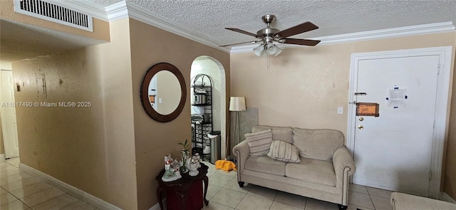 living area with ceiling fan, ornamental molding, a textured ceiling, and light tile patterned floors