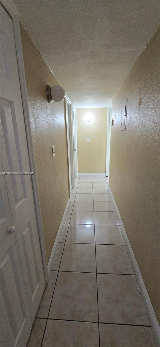 hallway featuring light tile patterned floors and a textured ceiling