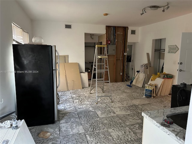 kitchen featuring light tile floors, rail lighting, and black fridge