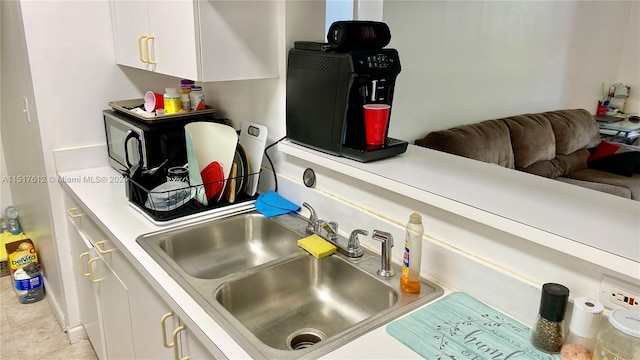 kitchen with white cabinetry, light tile floors, and sink