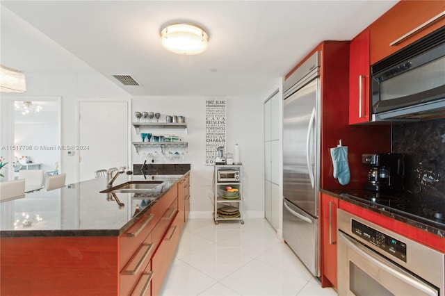 kitchen with dark stone countertops, sink, light tile floors, and black appliances