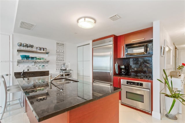 kitchen with light tile floors, a kitchen bar, black appliances, dark stone countertops, and sink