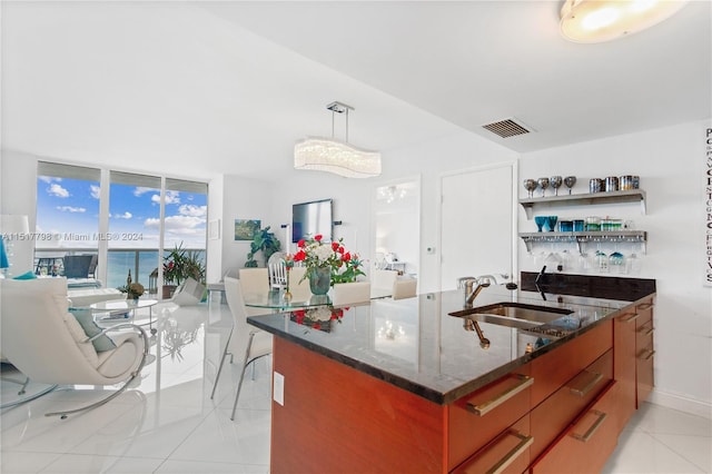 kitchen featuring expansive windows, sink, a water view, light tile floors, and dark stone counters