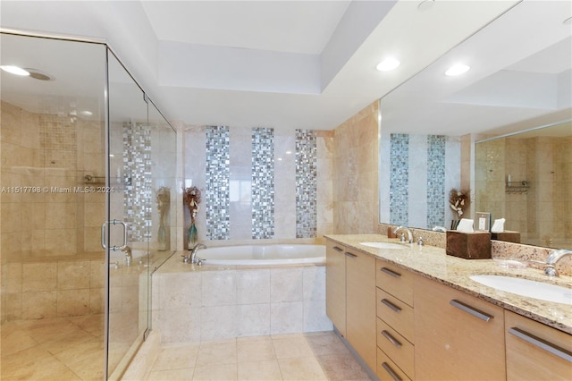 bathroom with tile walls, double sink, vanity with extensive cabinet space, independent shower and bath, and tile flooring