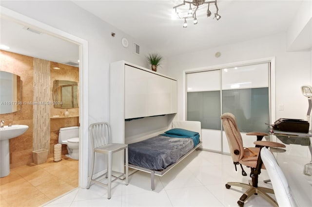 bedroom with light tile floors, a closet, ensuite bathroom, and tile walls