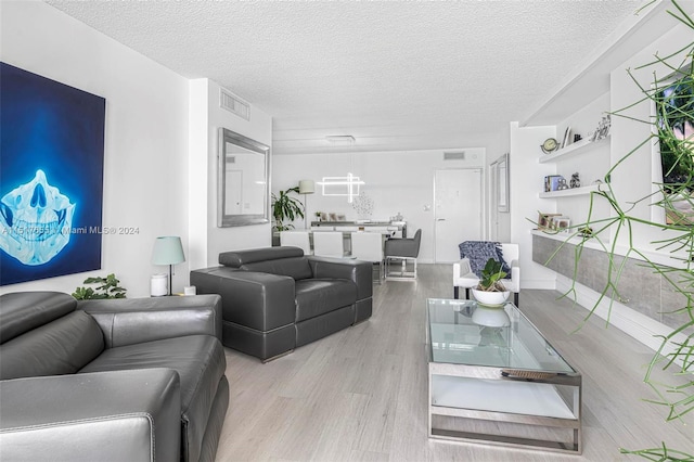 living room with a textured ceiling and light wood-type flooring