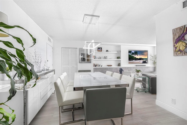 dining space featuring light hardwood / wood-style floors and a textured ceiling