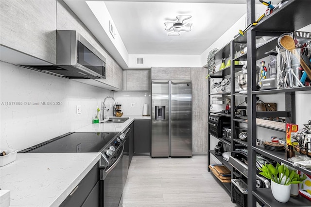 kitchen featuring black electric range oven, sink, gray cabinetry, light stone countertops, and stainless steel refrigerator with ice dispenser