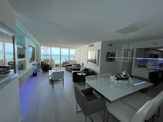 dining space featuring a water view, a textured ceiling, sink, and light hardwood / wood-style flooring