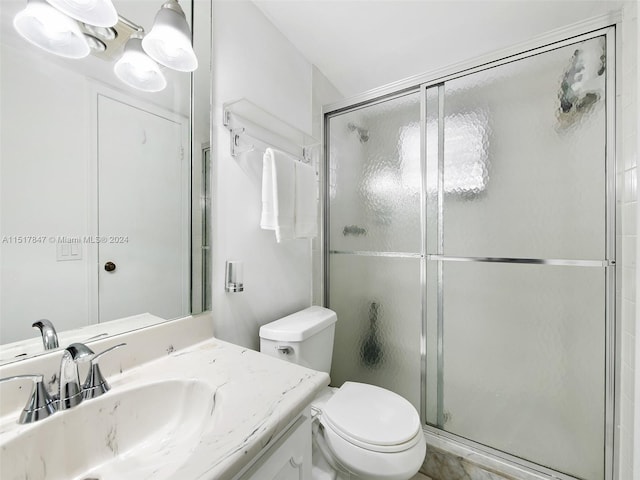 bathroom featuring a shower with door, toilet, and vanity