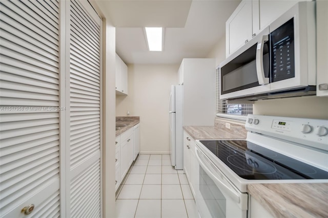 kitchen with white appliances, light tile flooring, and white cabinets