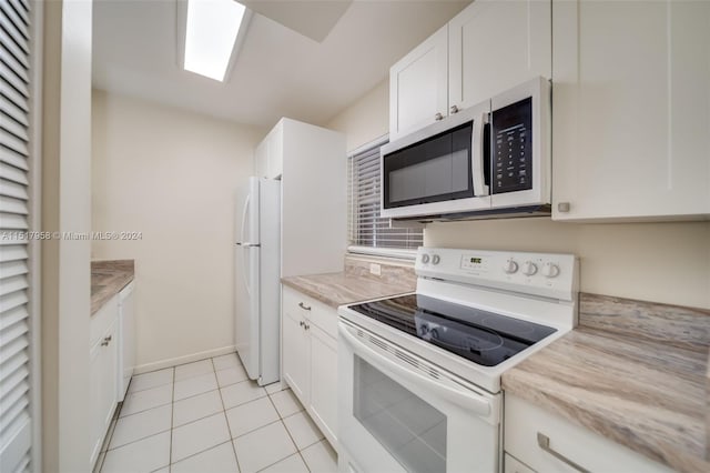 kitchen featuring white appliances, white cabinets, and light tile floors