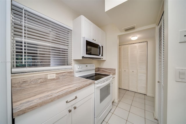 kitchen featuring light tile floors, white cabinets, and white electric stove