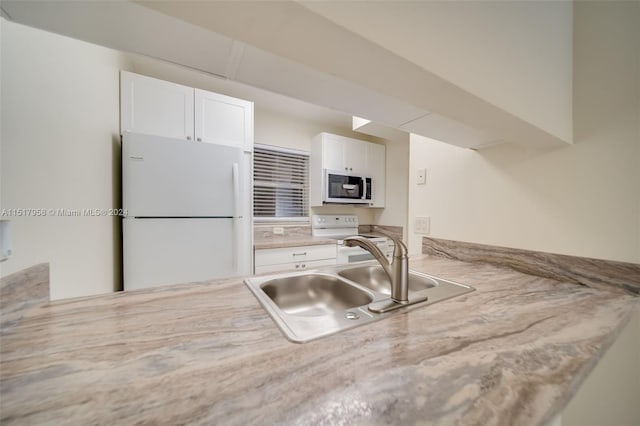 kitchen with white appliances, white cabinetry, and sink