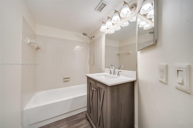 bathroom featuring tiled shower / bath combo, wood-type flooring, and large vanity