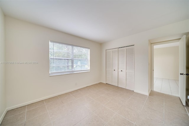 unfurnished bedroom with a closet and light tile floors