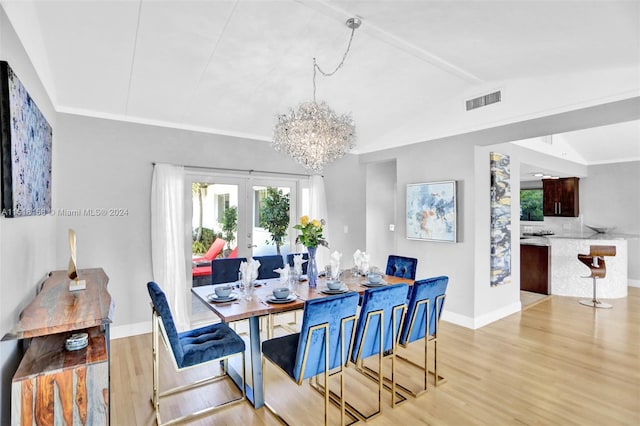 dining room featuring an inviting chandelier, lofted ceiling, light hardwood / wood-style floors, and french doors