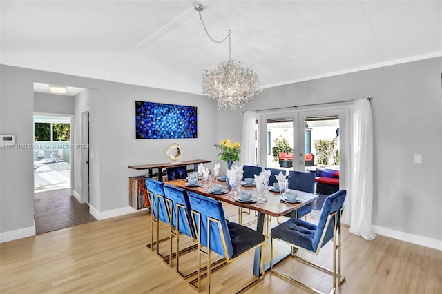 dining area featuring an inviting chandelier, lofted ceiling, light hardwood / wood-style floors, and french doors