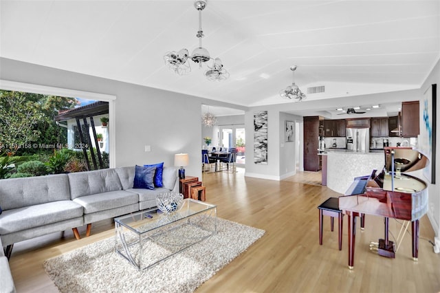 living room with lofted ceiling, ceiling fan with notable chandelier, and light hardwood / wood-style flooring