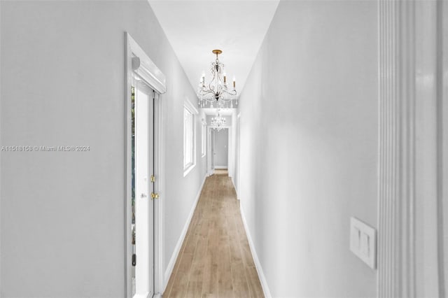 corridor featuring a notable chandelier and light hardwood / wood-style floors