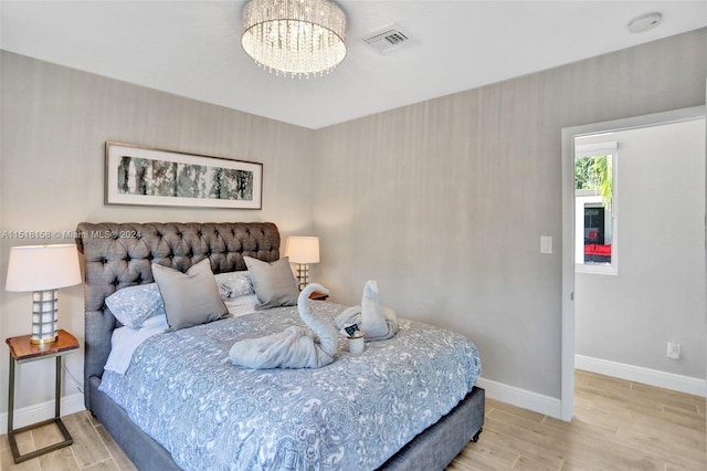 bedroom featuring an inviting chandelier and light wood-type flooring