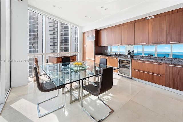 dining space with a water view, beverage cooler, light tile floors, and sink