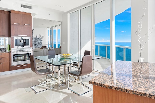 tiled dining space with a water view and floor to ceiling windows