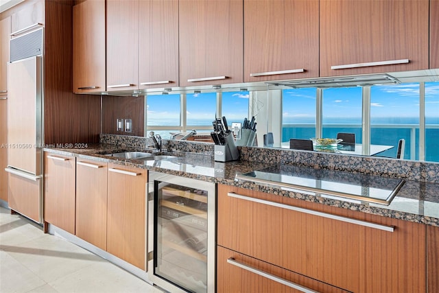 kitchen with light tile flooring, sink, a water view, wine cooler, and dark stone counters