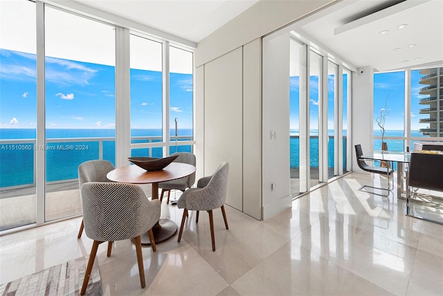 dining room with a water view, a wall of windows, and light tile floors