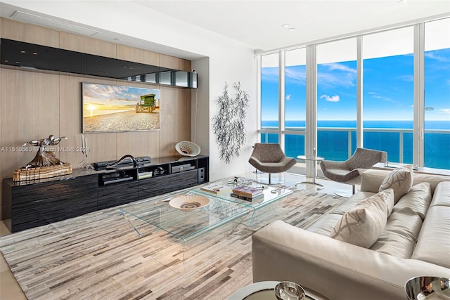 living room featuring floor to ceiling windows, a water view, and light hardwood / wood-style flooring