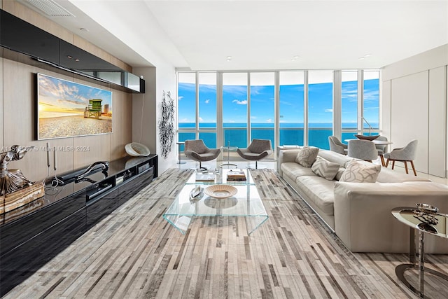 living room featuring a wall of windows, light hardwood / wood-style floors, a wealth of natural light, and a water view