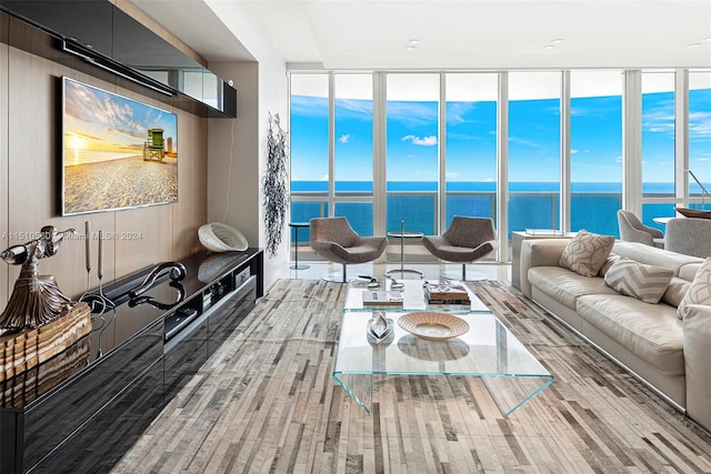 living room featuring floor to ceiling windows, light hardwood / wood-style floors, and a water view