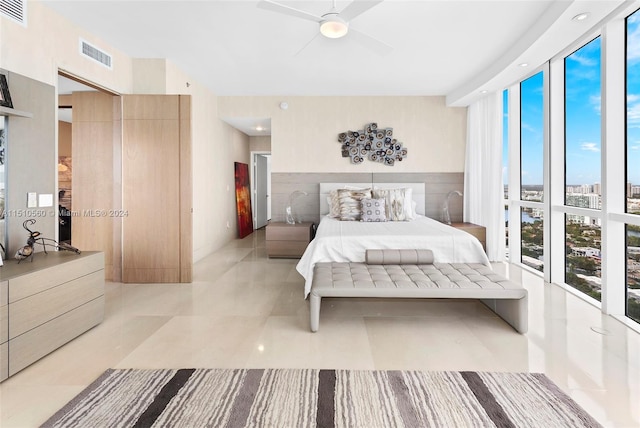 bedroom with a wall of windows, light tile floors, and ceiling fan