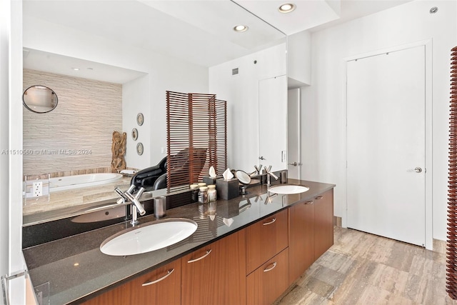 bathroom featuring dual vanity, a tub, and hardwood / wood-style flooring