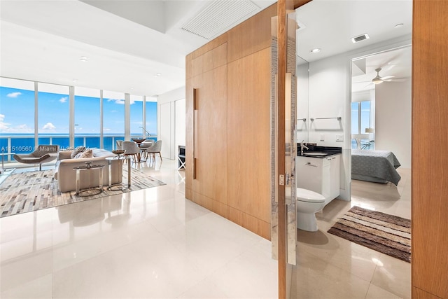 bathroom with toilet, tile flooring, ceiling fan, and a wealth of natural light